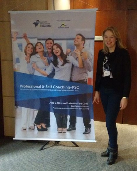 Sabrina em frente a um quadro informativo do PSC - Professional & Self Coaching