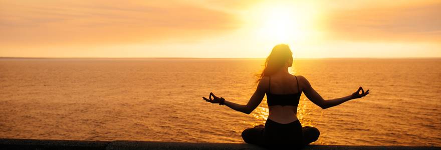 mulher medidando ao por do sol