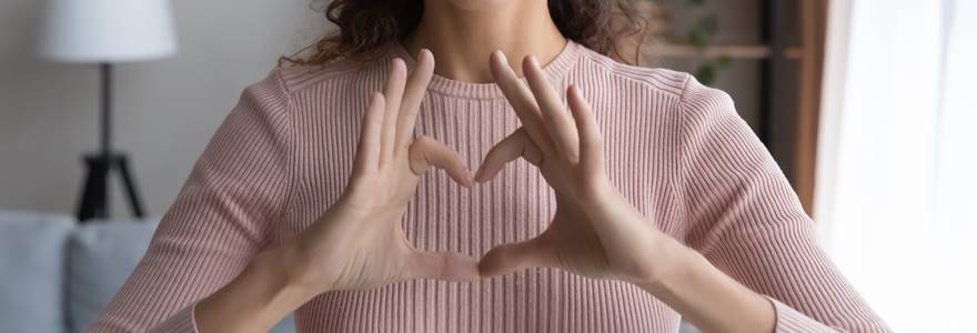 mulher fazendo o sinal de um coração com as mãos