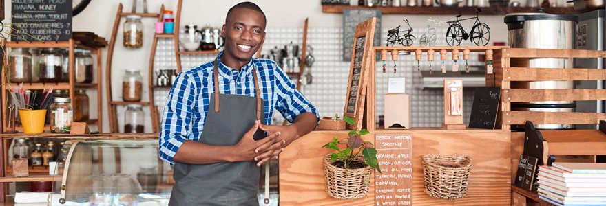 jovem empreendedor usando um avental e encostado no balcão de seu café