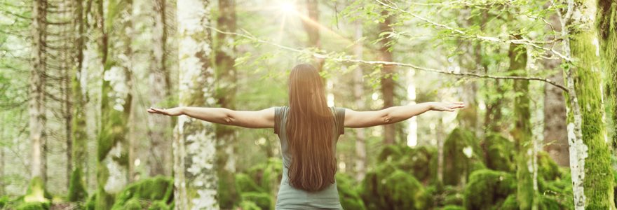 Mulher abrindo os braços na floresta